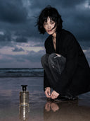Luxury fragrance campaign for Valloria Bliss perfume, showcasing a modern chic model on a coastal beach during a moody, overcast dusk.