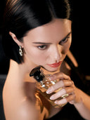 Valloria Bliss luxury perfume campaign featuring an elegant woman with a sleek black bob haircut holding a golden fragrance bottle.