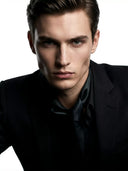 Valloria Kaptaan luxury perfume campaign featuring a sharp portrait of a male model in a tailored black suit against a clean white background.